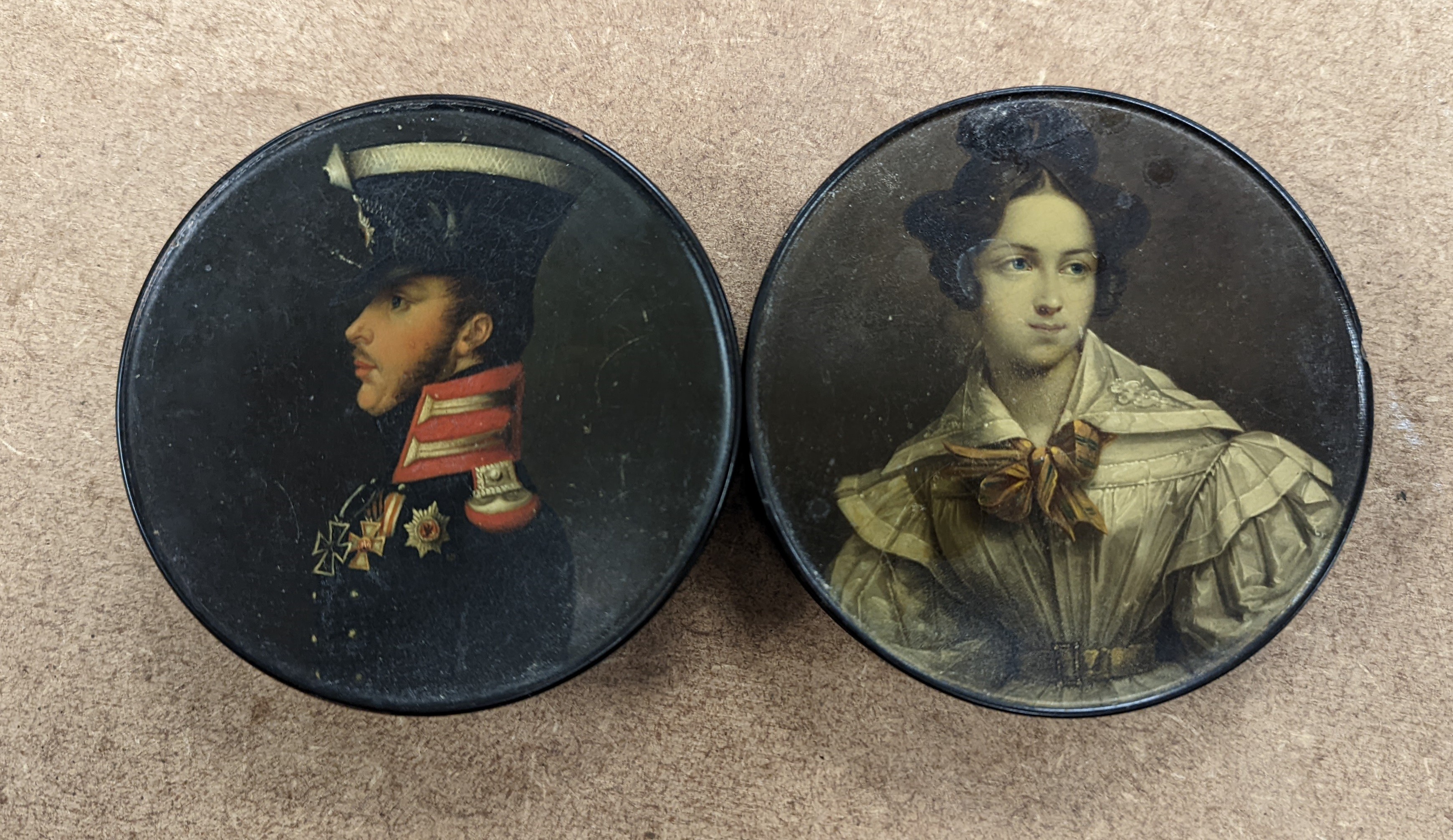 A 19th century Stobwasser papier mache ‘Henriette Sonntag’ portrait snuff box, c.1830, 9.7cm diameter and a 19th-century papier mache snuff box painted with a portrait of a German hussar, 9.4cm (2)